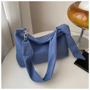 Close-up of blue fabric crossbody bag with minimalist knot detail and silver metal ring