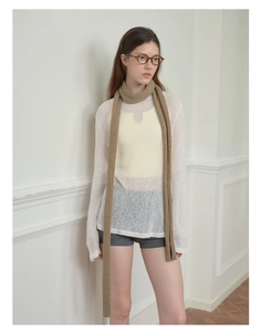 Close-up of a long slim brown knit scarf styled with a white crochet top for fall