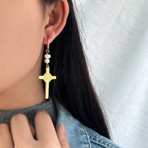 Boucles d'oreilles croix dorées avec perles sur mannequin, design vintage en acier