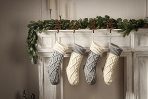 Detail of grey and white cable knit Christmas stockings hanging on a white fireplace