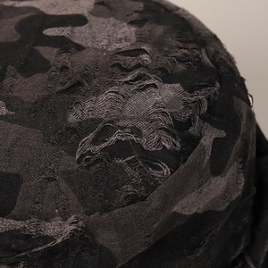 Detailed macro shot of distressed ripped edges and frayed fabric on camouflage bucket hat