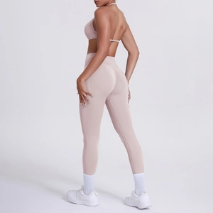 Dettaglio del reggiseno yoga incrociato e leggings a vita alta in tessuto rosa tenue
