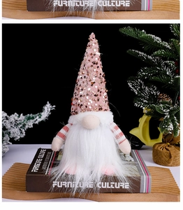 Pink sequin Christmas gnome doll sitting on a book with festive holiday background