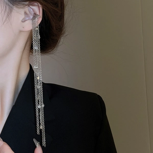 Close-up of silver tassel ear cuff with zircon stars on model wearing black blazer
