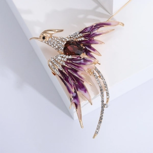 Detail of phoenix brooch with purple enamel wings and a large reddish-brown gemstone