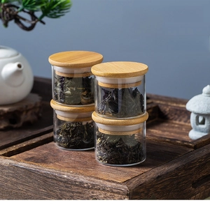 Close-up of portable mini glass tea jars with bamboo lids on a zen style wooden tray
