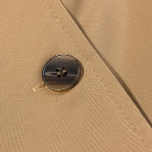 Close-up of khaki twill fabric with a dark brown tortoiseshell button on a trench coat