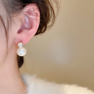 Elegant silver needle pearl and zircon stud earrings worn by a model in a close-up detail