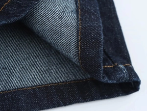 Gros plan sur le tissu denim indigo avec des coutures contrastées orange de haute qualité