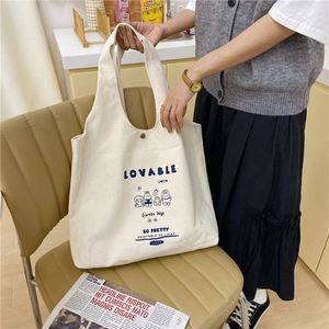 Détail d'un sac cabas en toile beige avec imprimé lapin et bouton pression en métal