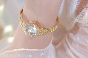 Close-up of a vintage golden square watch with rhinestone bezel on woman wrist