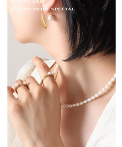 Close-up of elegant gold pearl earrings and necklace set on a fashion model