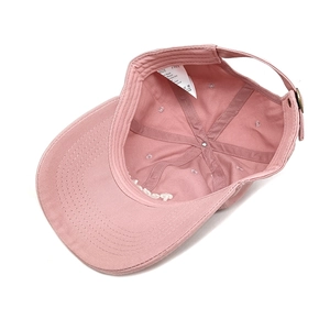 Detailed interior of pink cotton baseball cap showing 100% cotton label and metal strap