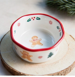 Ceramic Christmas bowl with gingerbread man motif and red scalloped edge on wood