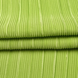 Close-up of green pleated fabric texture showing detailed ruffles on casual blouse