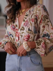 Detail of floral print long sleeve shirt with bohemian patterns and gold layered necklaces