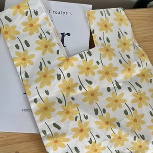 Detailed close-up of a floral cotton wristlet bag with yellow flowers on a wooden surface