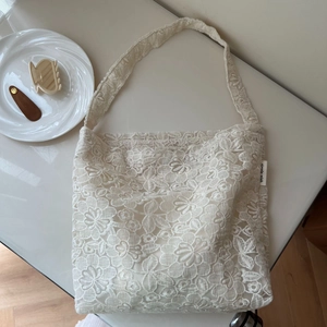 Close-up of white lace embroidery texture on a French style canvas shoulder bag