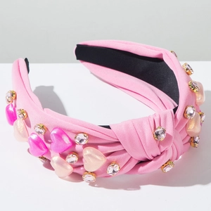Detalle de diadema rosa con nudo, corazones de diamantes de imitación y perlas
