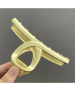 Close-up of a large golden metal shark hair claw clip with minimalist geometric design