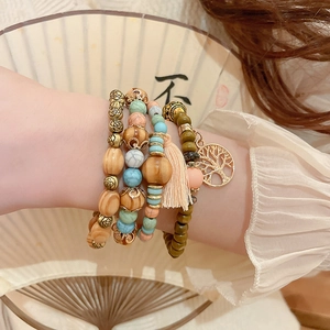 Detail of bohemian multilayer sandalwood beaded bracelet with tree of life charm and tassel