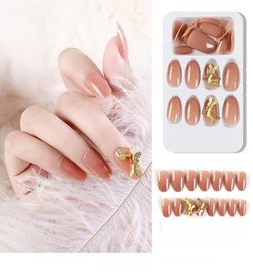 Detail of nude pink gradient press-on nails with 3D gold butterfly accents and 24pc set