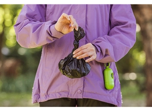 Close-up of portable capsule poop bag dispenser with LED light in an outdoor forest setting