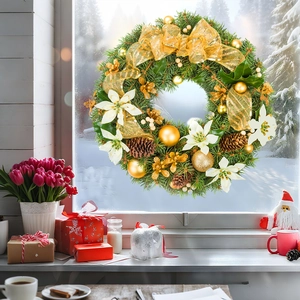 Close-up of a festive Christmas wreath with gold ornaments on a snowy winter window