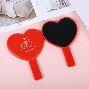 Cute heart-shaped handheld makeup mirrors in red and black on a pink background