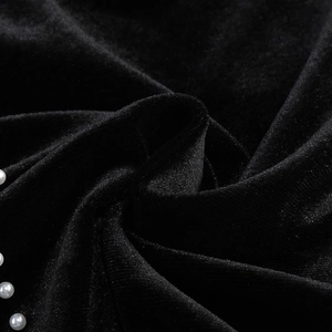 Détail du tissu en velours noir avec bordure de perles blanches et plis soyeux