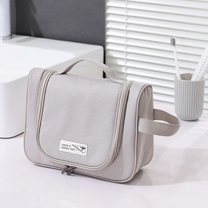 Detail view of grey travel toiletry bag with zipper and Have A Good Trip label