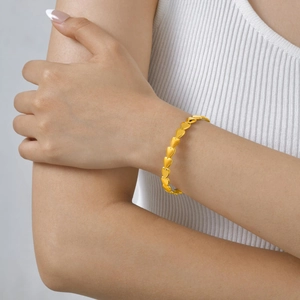 Detail of 18K gold-plated knotted C-shape cuff bracelet on model's wrist for daily wear