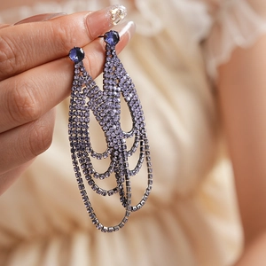 Detailed view of luxury purple rhinestone fringe earrings with silver needle tassels