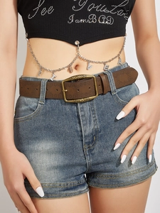 Detail of vintage brown embossed leather belt with antique bronze buckle on denim shorts