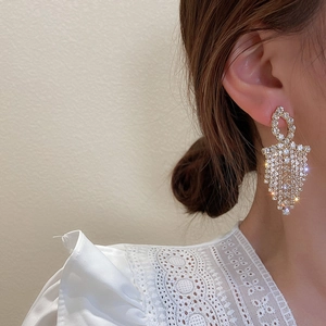 Close-up of sparkling gold tassel earrings with rhinestone fringe worn by a model