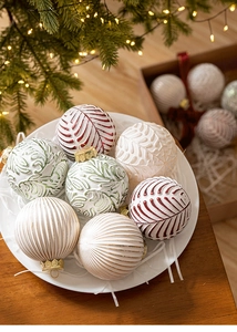 Detailed view of embossed Christmas ornaments in warm cream, green and red tones