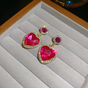 Gros plan de boucles d'oreilles cœur avec pierres rose rouge et finition dorée