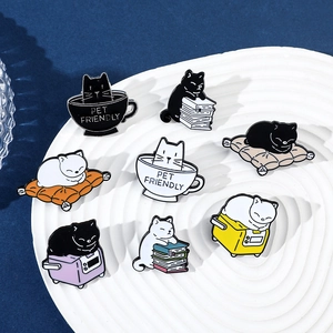 Flat lay detail of eight cute cartoon cat enamel pins on a white rippled display tray