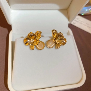 Close-up of golden flower stud earrings with opal stone set in a jewelry box