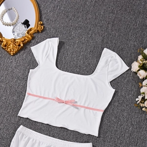 Close-up of white knitted crop top with pink ribbon bow on a textured gray background