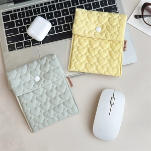 Close-up of quilted heart pattern storage bags with button closure on a desk set