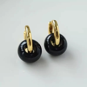 Detailed view of gold hoop earrings featuring polished black agate bead pendants