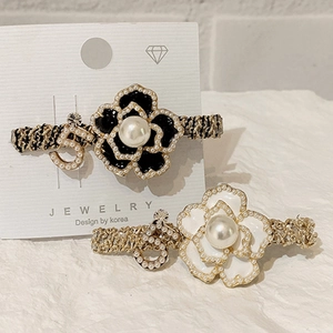 Detailed close-up of camellia hair clips with faux pearls and metal number 5 charms