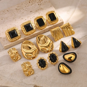 Vintage style gold and black enamel earrings and rings set on stone background
