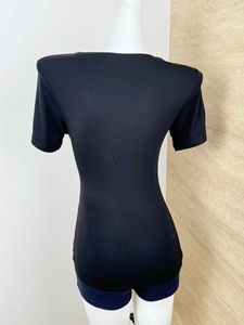 Rear view of a slim-fit black short-sleeve T-shirt on a model against a neutral wall