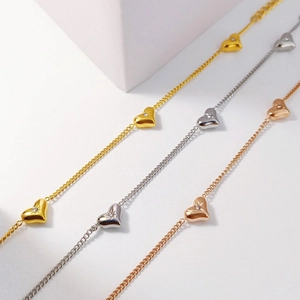 Detailed view of three heart pendants in gold, silver, and rose gold with starburst zircon