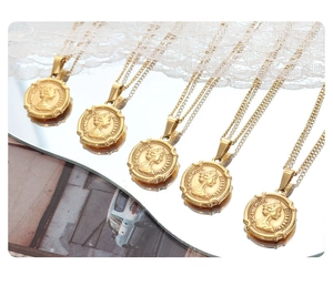 Detail of five golden necklaces with Queen Elizabeth II coin relief pendants on a mirror