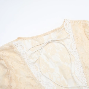 Detailed macro of floral lace pattern and tie-up neckline on cream summer dress