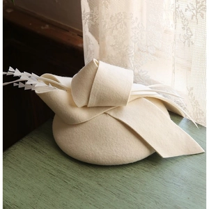Elegante cappellino fascinator in feltro di lana color crema con fiocco e piume