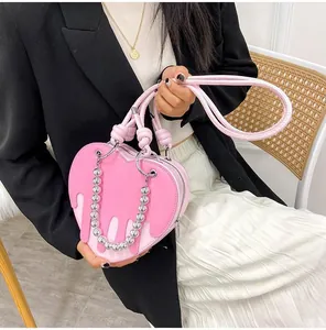 Detail of pink heart-shaped bag with dripping effect, woven handle and silver bead chain